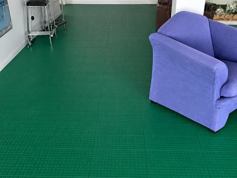 Sala de espera con piso plástico verde y un sillón